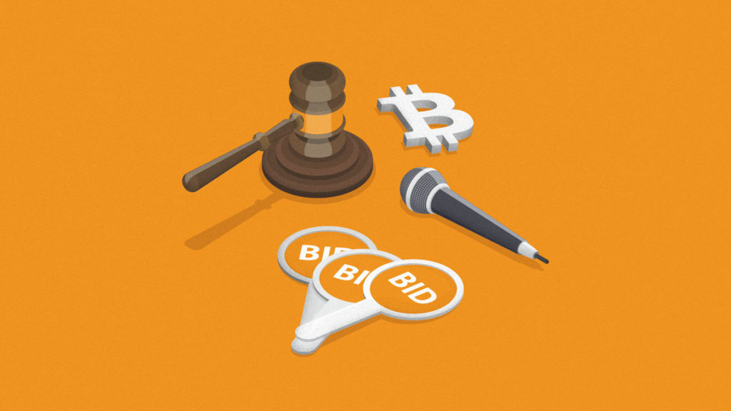 An auctioneer's gavel, auction paddles and a microphone sit on an orange background next to a Bitcoin symbol